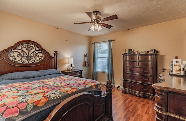 bedroom with a textured ceiling, ceiling fan, and light hardwood / wood-style flooring