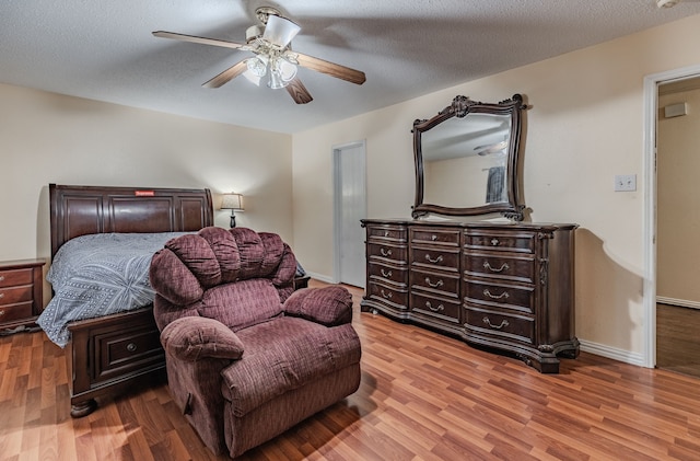 bedroom featuring light wood-type flooring, a textured ceiling, and ceiling fan