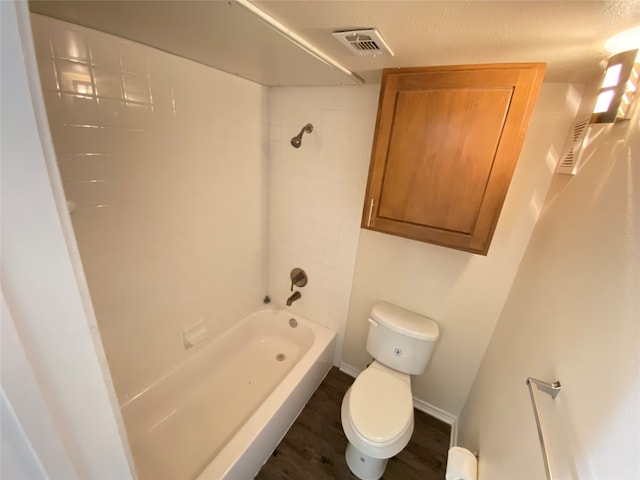 bathroom with hardwood / wood-style flooring, tiled shower / bath combo, and toilet