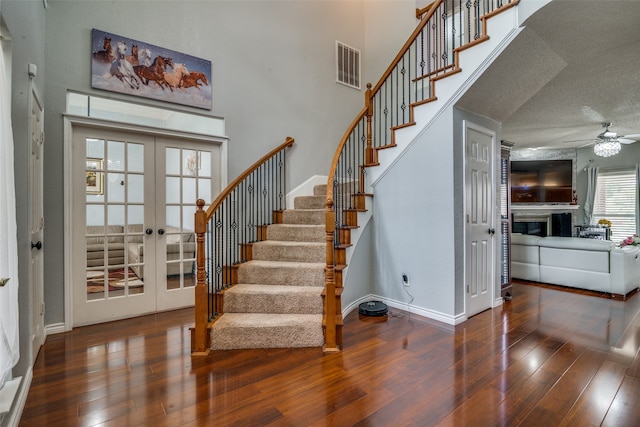 interior space featuring french doors, a textured ceiling, a towering ceiling, and hardwood / wood-style floors