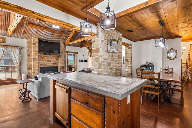 kitchen featuring a center island, wooden ceiling, a stone fireplace, vaulted ceiling with beams, and pendant lighting