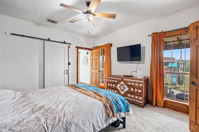 carpeted bedroom with ceiling fan and a barn door