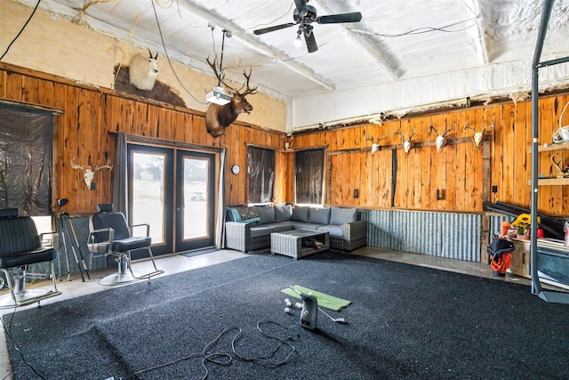 interior space with french doors, a towering ceiling, ceiling fan, and wooden walls