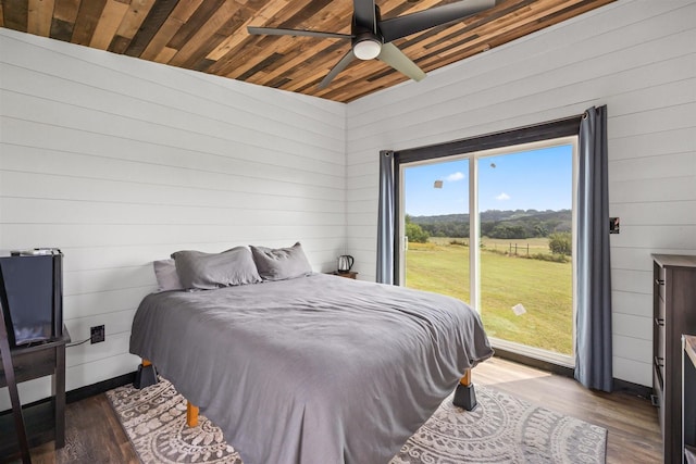 bedroom featuring vaulted ceiling, ceiling fan, hardwood / wood-style flooring, wooden ceiling, and wood walls