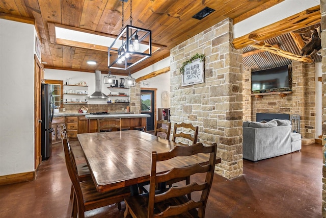 dining room featuring a stone fireplace, bar, and wooden ceiling