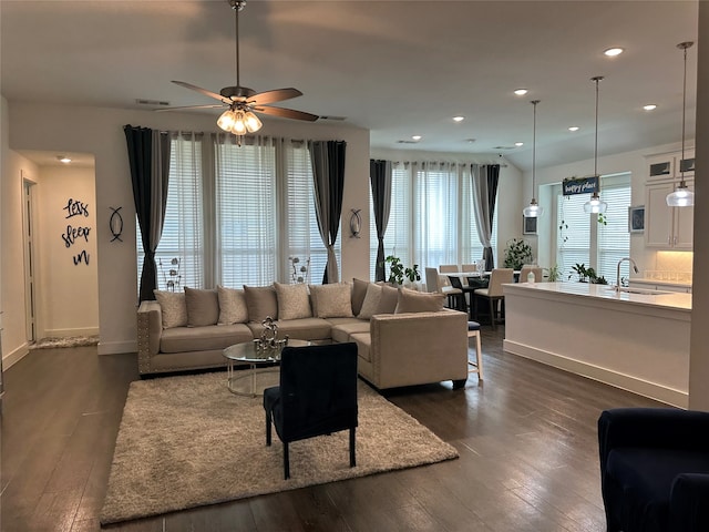 living room with ceiling fan, sink, and dark wood-type flooring