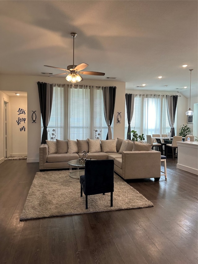 living room featuring ceiling fan and dark wood-type flooring