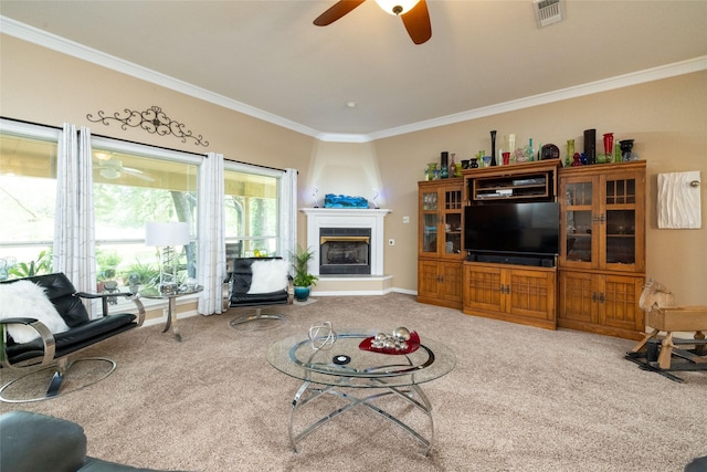 carpeted living room featuring a large fireplace, ceiling fan, and crown molding