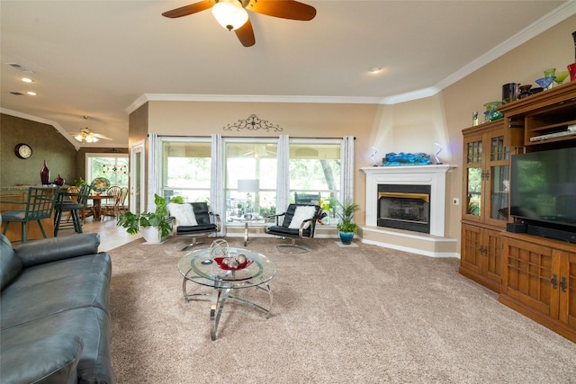 carpeted living room featuring a fireplace, ceiling fan, and crown molding