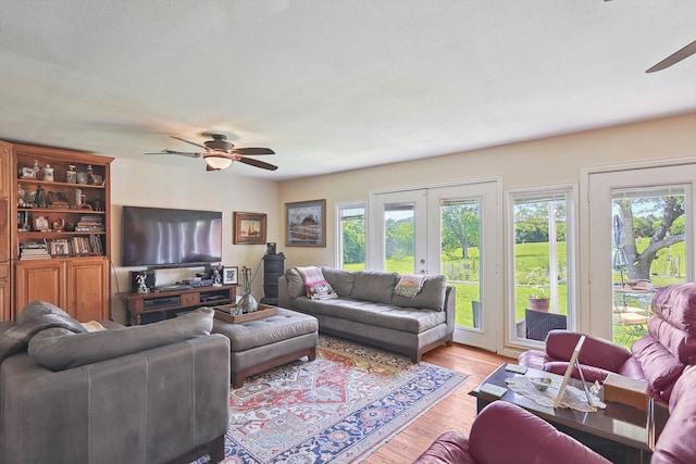 living room with plenty of natural light, ceiling fan, light wood-type flooring, and french doors