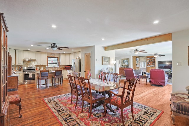 dining space with hardwood / wood-style floors, ceiling fan, and beam ceiling