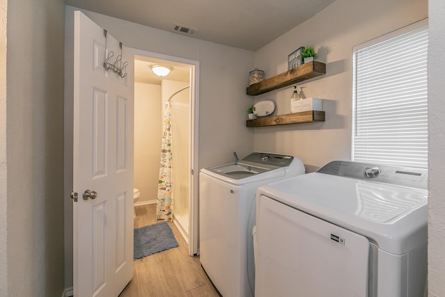 laundry area featuring separate washer and dryer and light hardwood / wood-style flooring