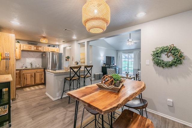 dining space with ceiling fan, sink, vaulted ceiling, and hardwood / wood-style flooring