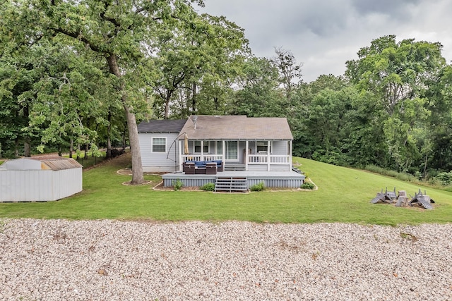 rear view of property featuring a wooden deck, a yard, and a shed