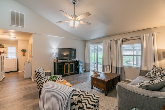 living room featuring hardwood / wood-style floors, ceiling fan, independent washer and dryer, and vaulted ceiling