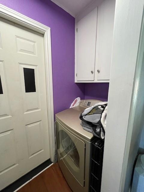 clothes washing area with washer and clothes dryer, dark hardwood / wood-style flooring, and cabinets