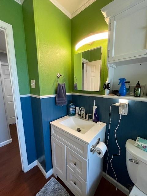 bathroom with hardwood / wood-style flooring, toilet, vanity, and ornamental molding