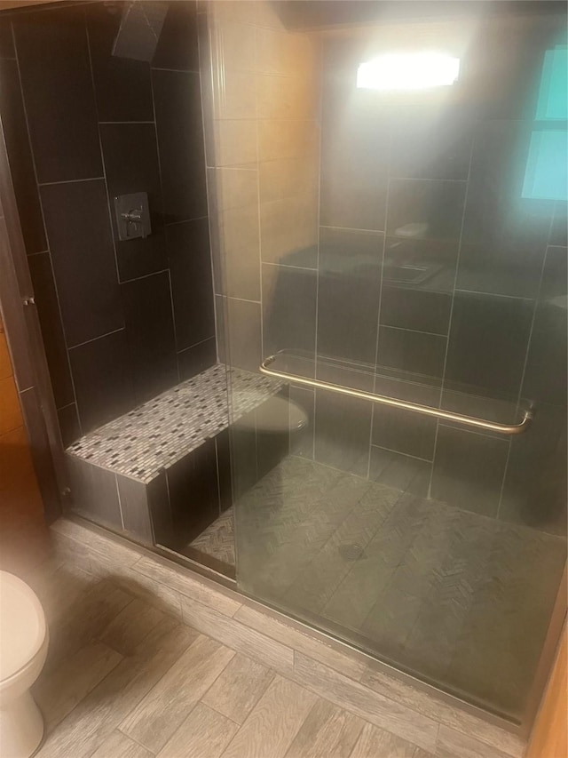 bathroom featuring toilet, a stall shower, and wood tiled floor