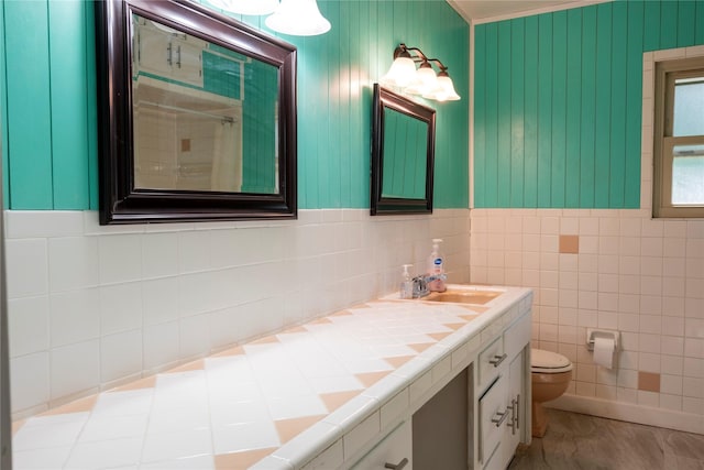 bathroom with crown molding, toilet, vanity, a shower with shower curtain, and tile walls