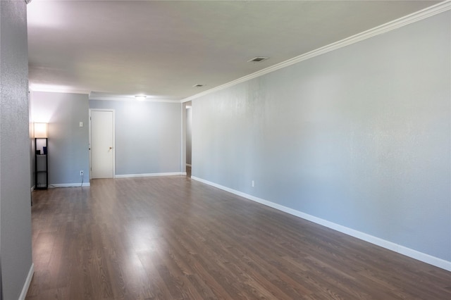 spare room with dark wood finished floors, visible vents, baseboards, and ornamental molding