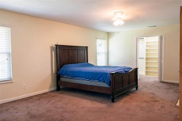 carpeted bedroom with a spacious closet, multiple windows, baseboards, and visible vents