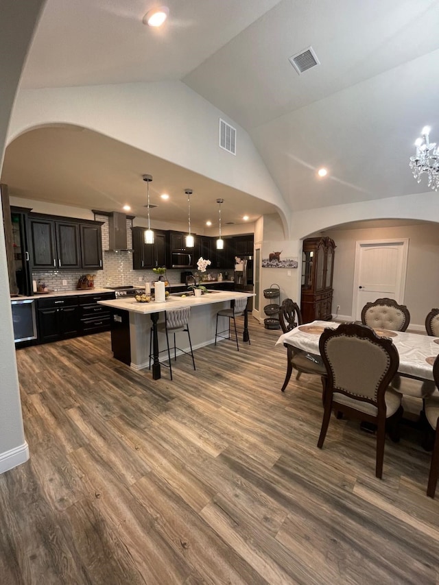 dining space with a chandelier, wood-type flooring, and vaulted ceiling