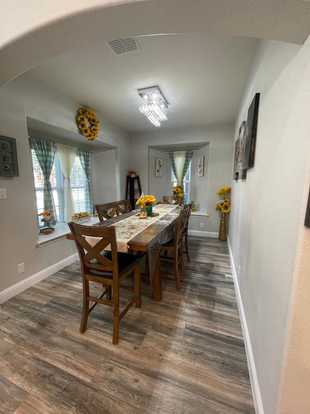 dining area with dark hardwood / wood-style floors and an inviting chandelier