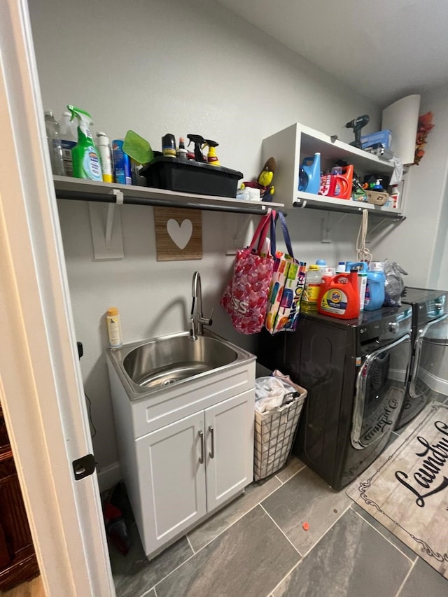 clothes washing area featuring dark tile patterned floors, cabinets, independent washer and dryer, and sink