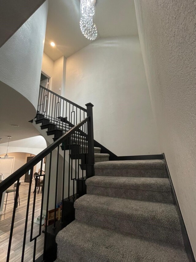 stairs with wood-type flooring and a notable chandelier