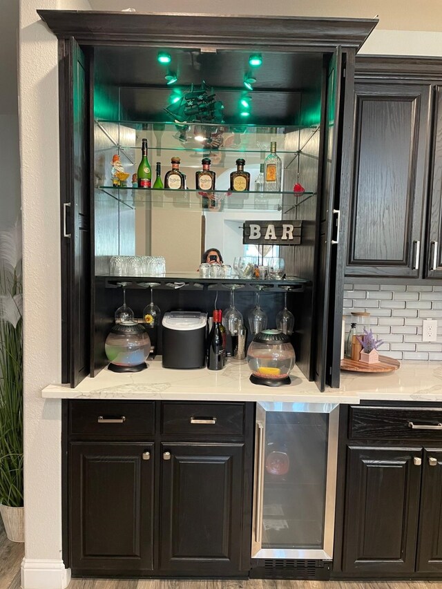 bar with decorative backsplash, light hardwood / wood-style floors, and wine cooler