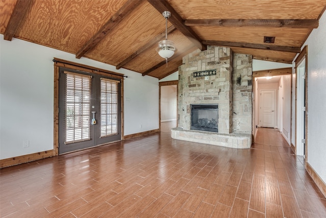 unfurnished living room with a fireplace, hardwood / wood-style floors, high vaulted ceiling, beamed ceiling, and french doors