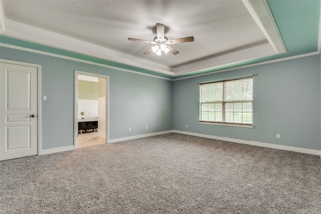 unfurnished bedroom featuring ceiling fan, carpet, ornamental molding, and a tray ceiling