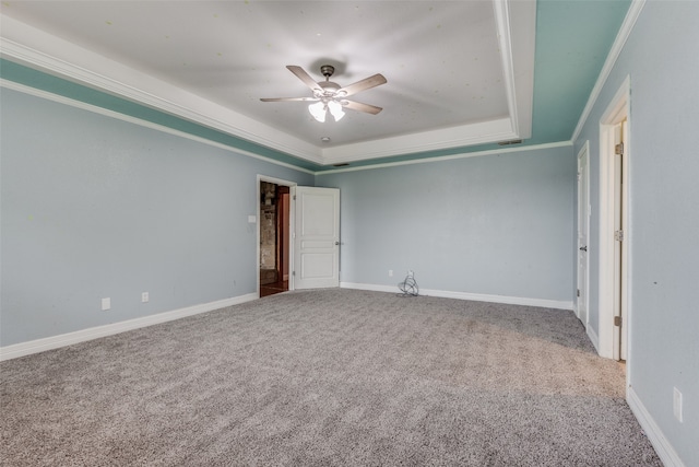 spare room featuring carpet flooring, ornamental molding, ceiling fan, and a raised ceiling