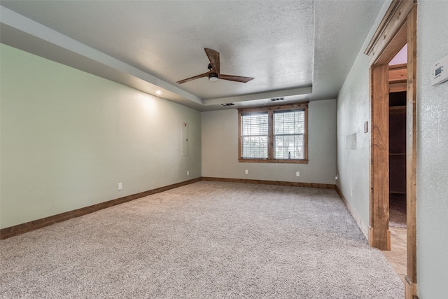 unfurnished bedroom featuring light colored carpet, a textured ceiling, ceiling fan, and a raised ceiling