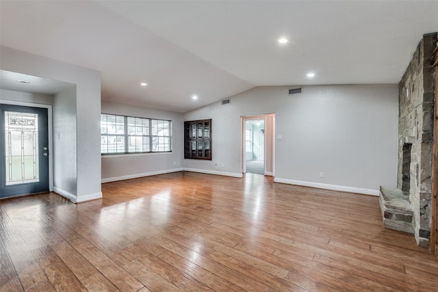 unfurnished living room featuring a stone fireplace, vaulted ceiling, and hardwood / wood-style flooring