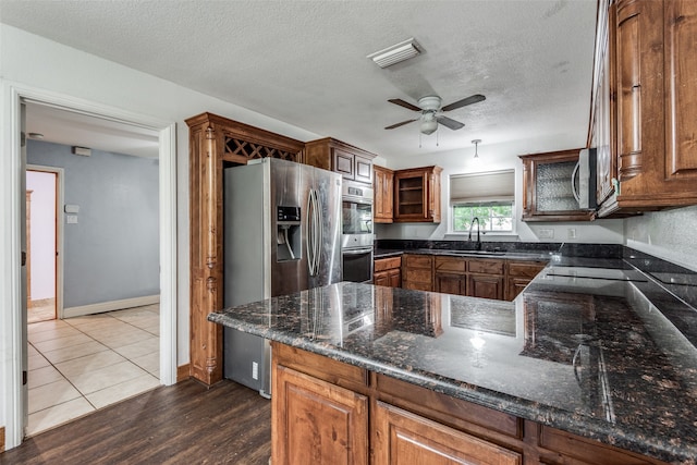 kitchen featuring ceiling fan, hardwood / wood-style floors, dark stone countertops, sink, and appliances with stainless steel finishes