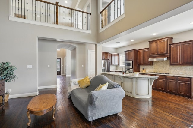 living room with dark wood-type flooring and a towering ceiling