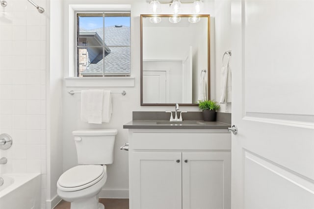 full bathroom with tiled shower / bath, vanity, and toilet