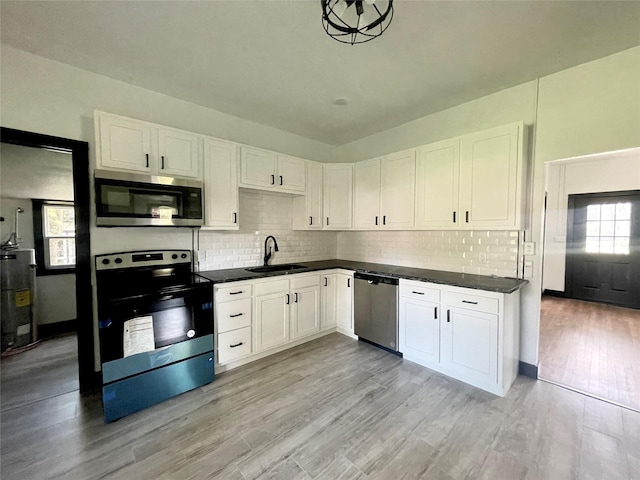 kitchen featuring appliances with stainless steel finishes, light wood-type flooring, water heater, sink, and white cabinets