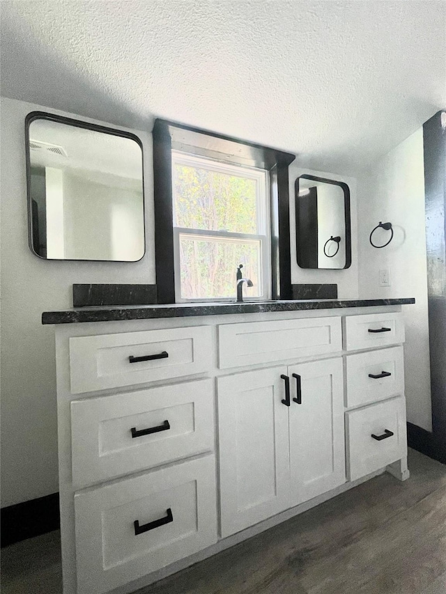 bathroom with a textured ceiling, vanity, and hardwood / wood-style floors