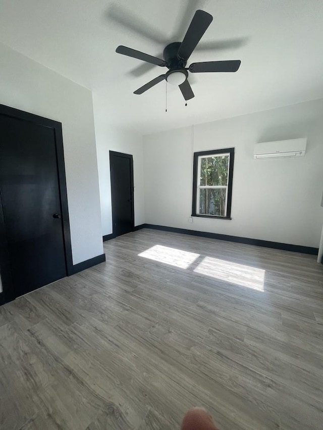 interior space with ceiling fan, light hardwood / wood-style flooring, and a wall mounted AC