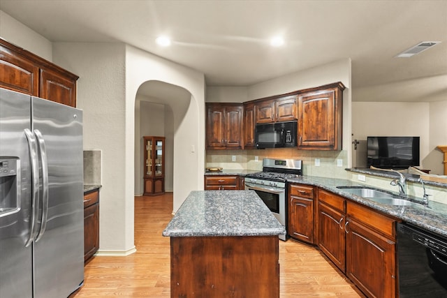 kitchen featuring decorative backsplash, light wood-type flooring, sink, black appliances, and a center island