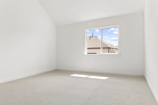 carpeted empty room featuring vaulted ceiling