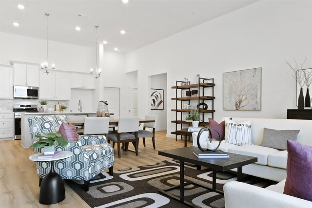 kitchen with a center island with sink, appliances with stainless steel finishes, light hardwood / wood-style flooring, and white cabinets