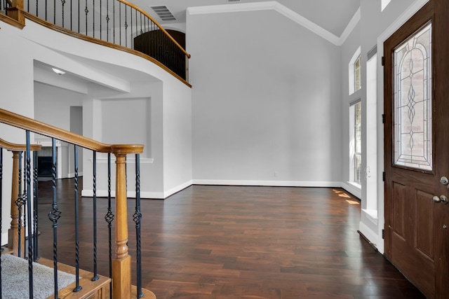 foyer entrance featuring crown molding, dark wood-type flooring, and high vaulted ceiling