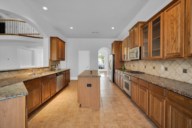 kitchen featuring a center island, sink, dark stone countertops, light tile patterned floors, and stainless steel appliances