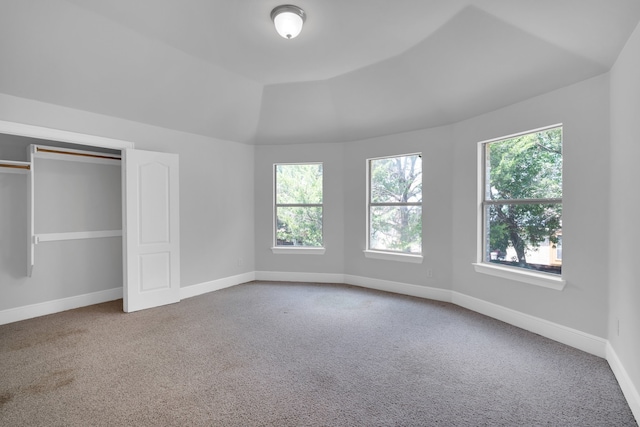 unfurnished bedroom featuring carpet flooring, multiple windows, and vaulted ceiling