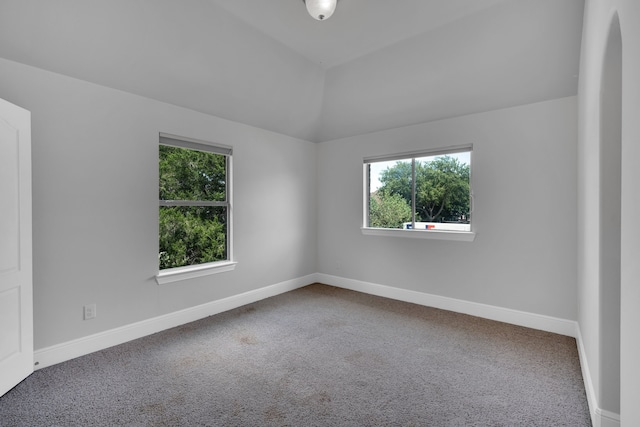 carpeted empty room featuring vaulted ceiling