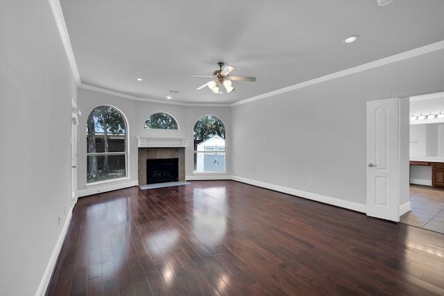 unfurnished living room with a tile fireplace, ceiling fan, wood-type flooring, and ornamental molding