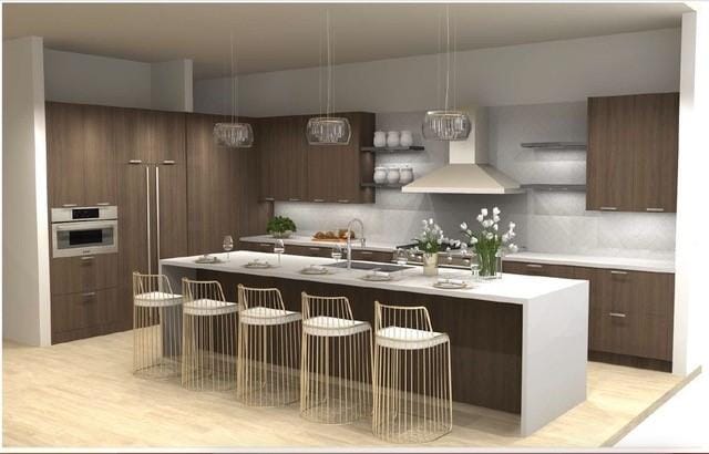 kitchen with modern cabinets, a kitchen island with sink, a sink, wall oven, and wall chimney range hood